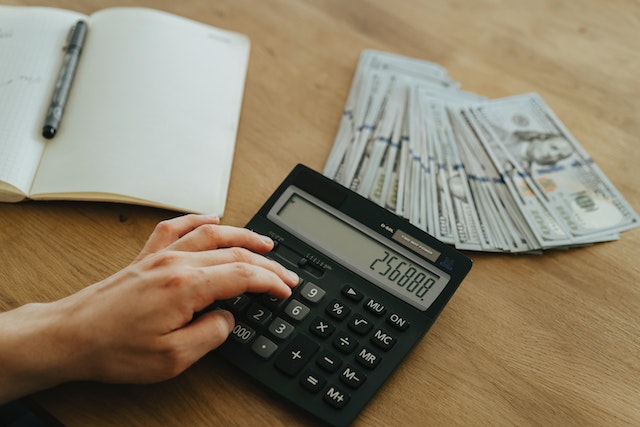 person using calculator to count the bills on the desk